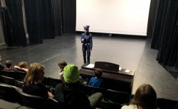 6 policjantka ruchu drogowego w sali kinowej przekazuje młodzieży zasady bezpieczeństwa w ruchu drogowym