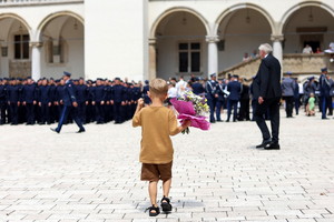 kilkuletni chłopiec idący z kwiatami do mamy, która została policjantką