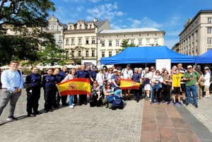 hiszpańska wycieczka pozuje z policjantami na rynku przy stoisku