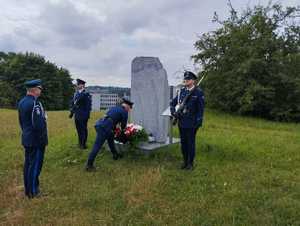 policjanci kładą wieniec pod obeliskiem