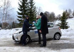 Przewodnicząca Rady Miejskiej przekazuje Komendantowi kluczyki do radiowozu, w tle nowy pojazd slużbowy
