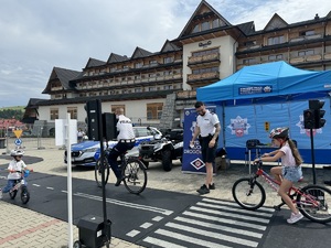 2 dzieci korzystające z mini miasteczka rowerowego pod opieką policjantów drogówki