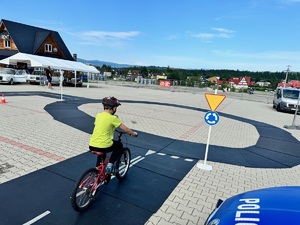 3 dziecko poruszające się rowerem po mini miasteczku ruchu drogowego