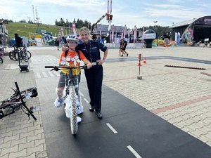 4 dziecko na rowerze pozuje do zdjęcia z policjantką ruchu drogowego
