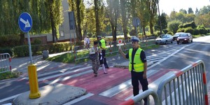 Policjanci Ruchu Drogowego stojąc na przejściu dla pieszych kierują ruch...