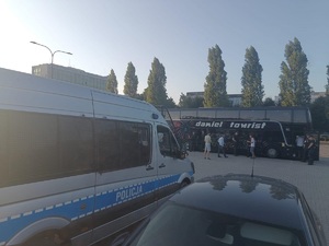 Pojazd odziałów prewencji, w tle autokar z kibicami