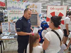 policjant wręcza kobiecie ulotkę o Krajowej Mapie Zagrożeń Bezpieczeństwa