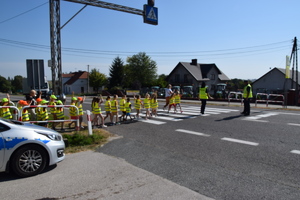 uczniowie orzechodzę orzez przejście dla pieszych w ramach akcji bezpieczna droga do szkoły