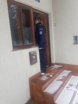 policjant stojący w progu domu - kontrola osoby samotnie zamieszkującej