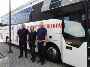 troje umundurowanych policjantów stojących przed krwiobusem