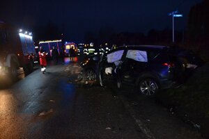 miejsce wypadku drogowego w Dąbrowie Szlacheckiej-pojazd leżący częściowo w rowie, w tle ratownicy i straż pożarna