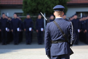 Policjant warty honorowej. Przed nim ślubujący policjnaci