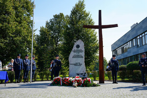 pomnik i krzyż ze złożonymi kwiatami