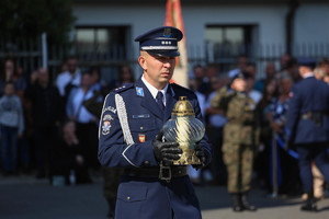 policjant niesie znicz pod pomnik i krzyż