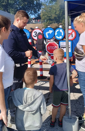 policjant rozdający dzieciom ulotki przy policyjnym stoisku