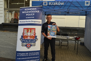 Policjant ruchu drogowego trzyma w rędku plakat