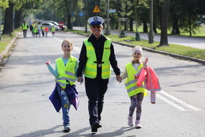 policjantka idzie za ręce z dwójką dzieci