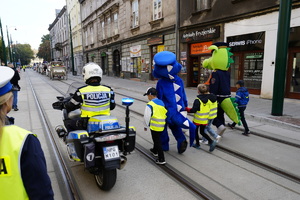 polisia trzyma za ręce dzieci obok motocyklista policyjny