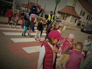 policjnt z grupką dzieci przechodzi przez przejście dla pieszych