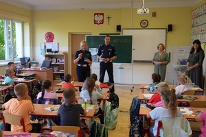 Policjancji  ruchu drogowego podczas prelekcji w szkole, rozmawiający z dziećmi o ich bezpieczeństwie na drodze