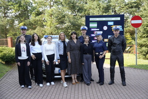 Zdjęcie zbiorowe przedstawiające policjantów ruchu drogowego  i uczniów na tle radiowozu i tablicy z Europejskim Tygodniem Mobilności