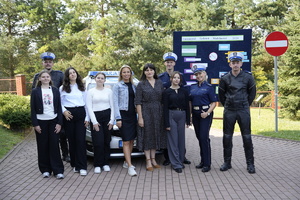 Zdjęcie zbiorowe przedstawiające policjantów ruchu drogowego  i uczniów na tle radiowozu i tablicy z Europejskim Tygodniem Mobilności