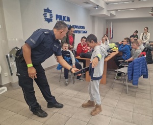 policjant sprawdza wykrywaczem metalu chłopca
