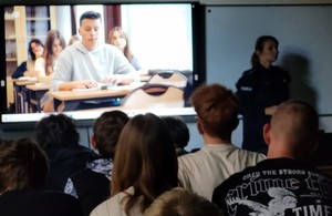 film edukacyjny na ekranie, przed nim siedzące dzieci i stojąca policjantka (2)