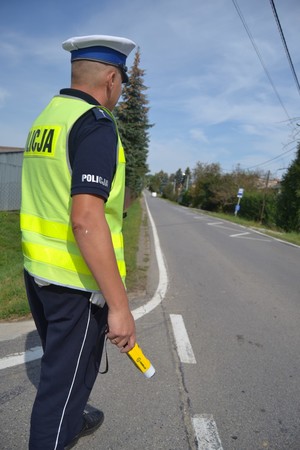 Policjant Ruchu Drogowego stojący przy drodze, trzymający urządzenie do badania trzeźwości 2