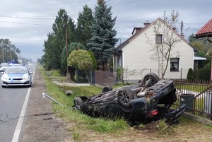 samochód, który dachował obok posesji w tle radiowóz