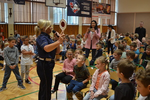 Policjantka pokazuje uczniom tarczę do zatrzymywania pojazdów