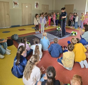 KPP Oświęcim. Bezpieczna droga do szkoły 2024 policyjne prelekcje policjantka i dzieci przy makiecie przejścia dla pieszych (1)