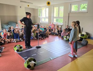 KPP Oświęcim. Bezpieczna droga do szkoły 2024 policyjne prelekcje policjantka i dzieci przy makiecie przejścia dla pieszych (3) dziewczynk przed makietą przejścia