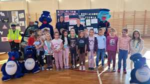 uczniowie wraz z policjnatka i maskotkami policyjnymi