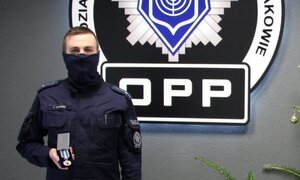 policjant pozuje przed znakiem OPP