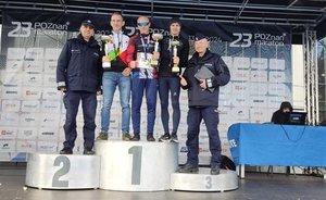 Zwcięzcy maratonu i dwóch policjantów ubranych w mundury stoi na podium