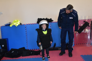 Umundurowany policjant oraz przedszkolak w policyjnym kasku i kamizelce policyjnej