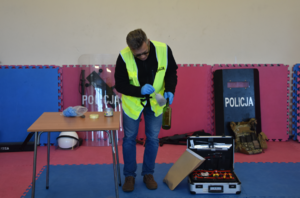 Policyjny technik podczas prezentacji procedury zabezpieczania odcisków palców z butelki