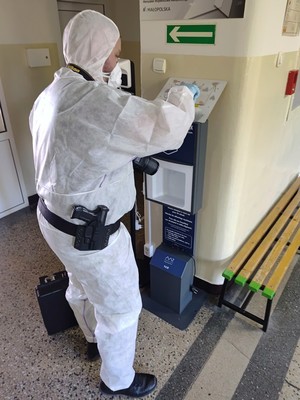 Policjant ubrany w biały kombinezon zabepieczający slady na miesjcu zdarzenia.