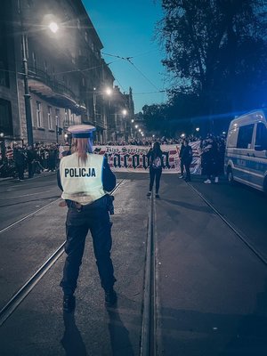 policjantka stoi przed kibicami z banerem