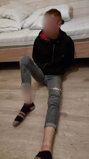 zatrzymany siedzi przy łóżku skuty kajdankami