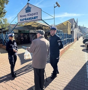 policjanci wręczający przechodniom odblaski