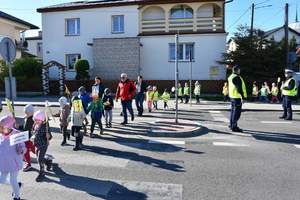 Policjanci kierują ruchem podczas akcji Kierowco, proszę zwolnij . Przedszkolaki przechodzą przez oznakowane przejsćie dla pieszych