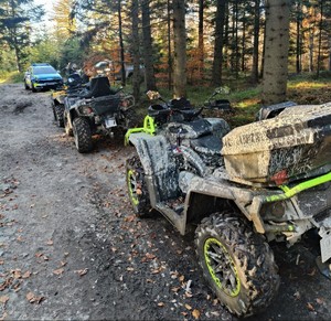 dwa zatrzymane do kontroli quady, w tle policyjny radiowóz