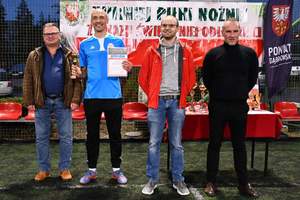 Kapitan drużyny policjantów odbiera puchar i pamiatkowy dyplom