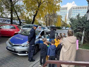 dzieci w towarzystwie policjantki oglądają radiowóz