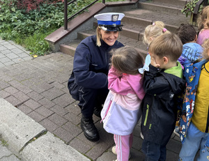 policjantka przed budynkiem rozmawia z przedszkolakami