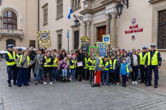 dzieci trzymające transparenty w towarzystwie policjantów przed Urzędem Miasta Krakowa