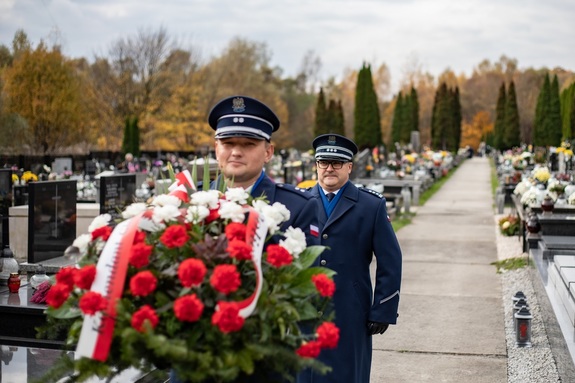 Policjant niosący wieniec za nim komendant wojewódzki