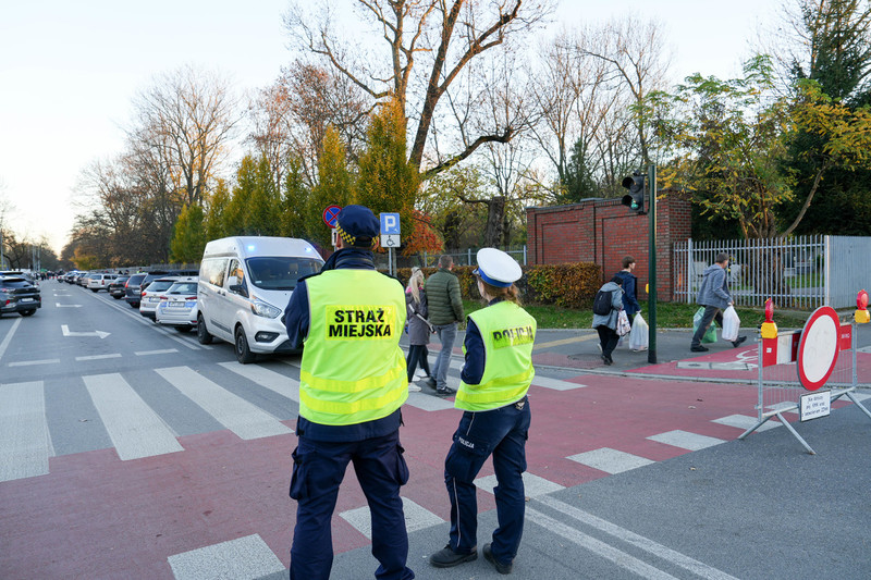 policjantka i strażnik miejski przy przejściu dla pieszych obok cmentarza rakowickiego